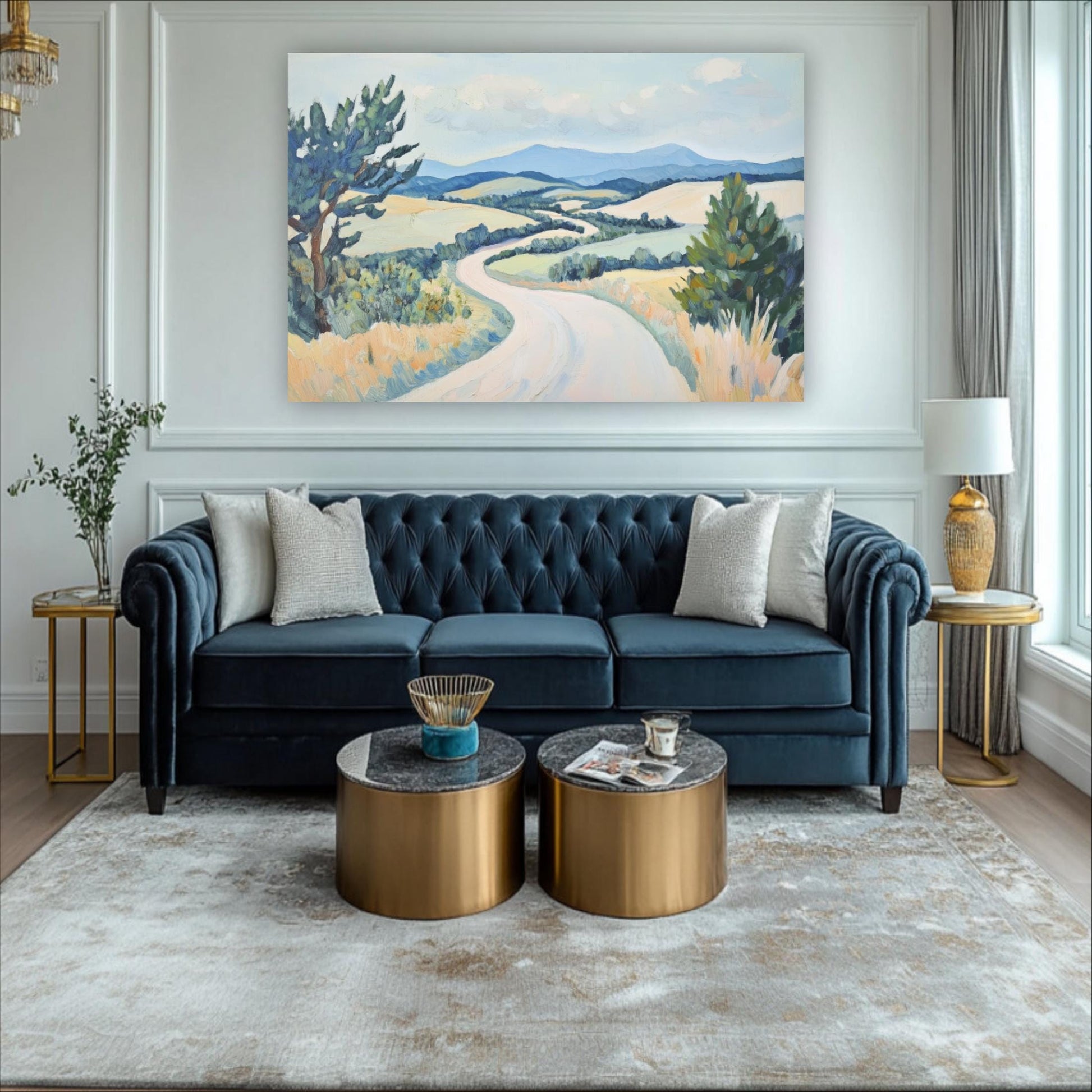 a living room with a blue tufted sofa, two round coffee tables, and a large landscape painting on the wall.