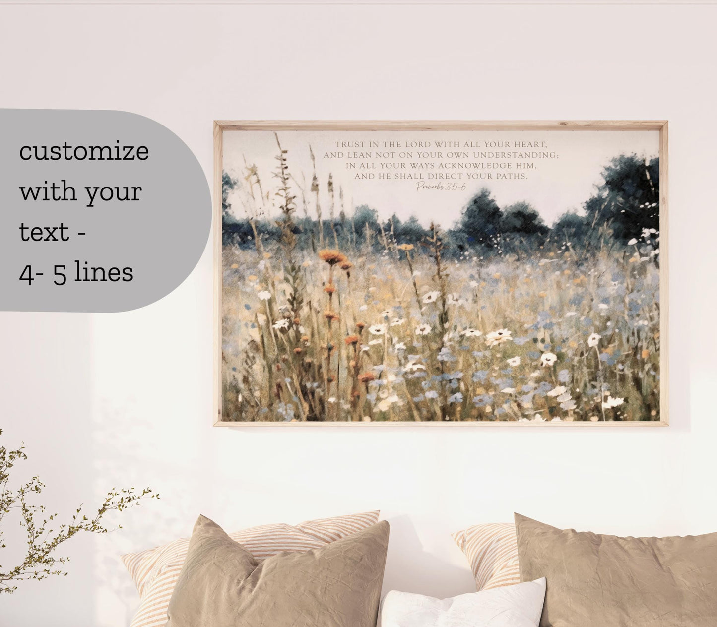 a framed painting of a field of flowers hanging on a wall, with two pillows below it.