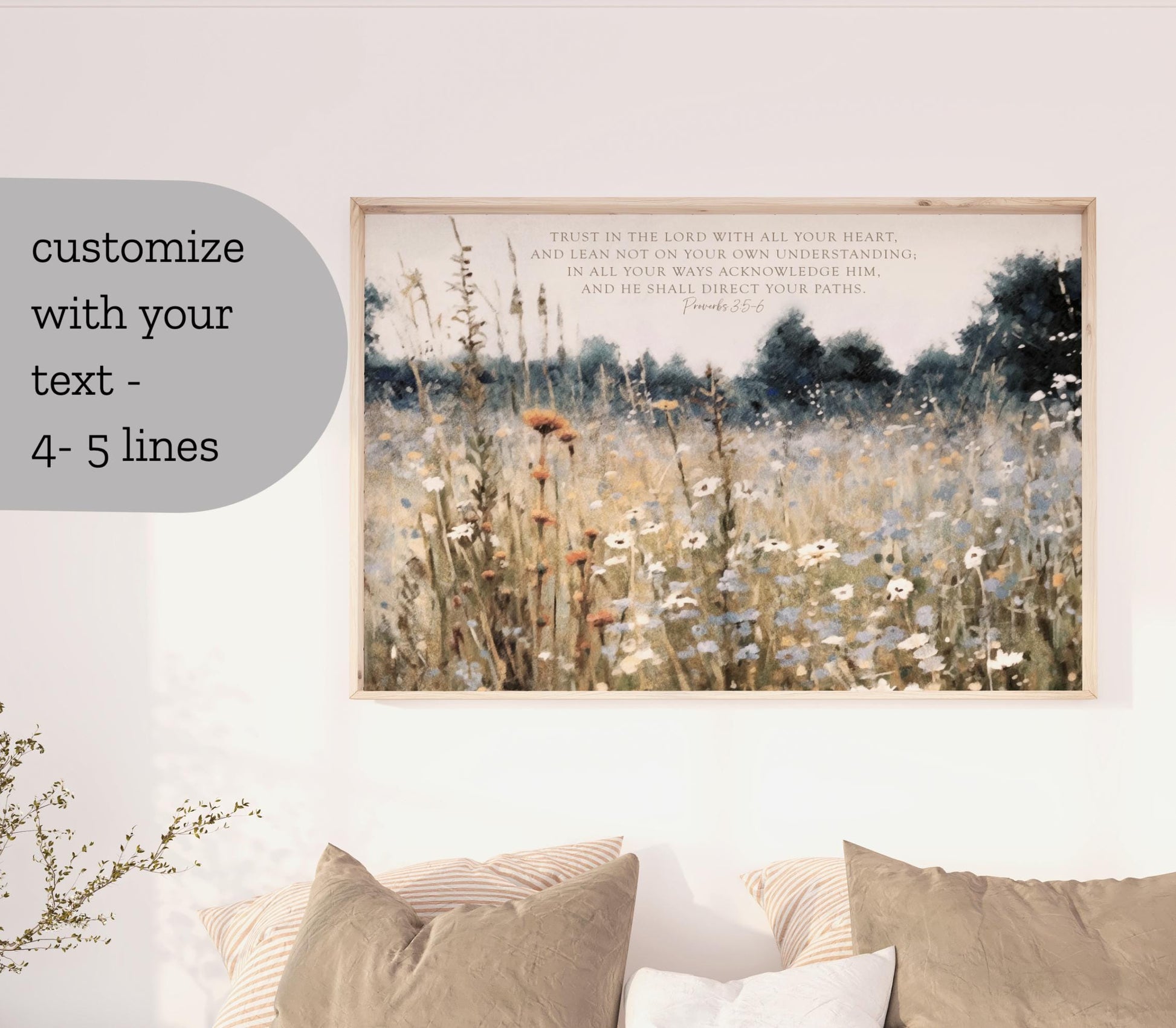 a framed painting of a field of flowers hanging on a wall, with two pillows below it.