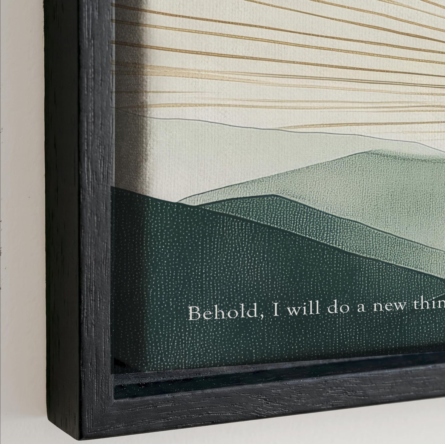 The image is a framed artwork depicting a landscape with mountains and hills. The text on the frame reads "Behold, I will do a new thing".