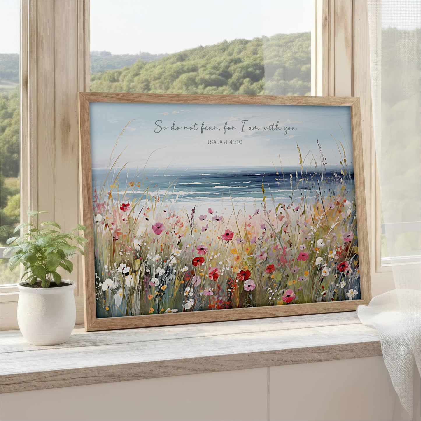 A framed painting depicting a serene landscape with a field of colorful flowers and a body of water, with a quote from the Bible visible in the top right corner.