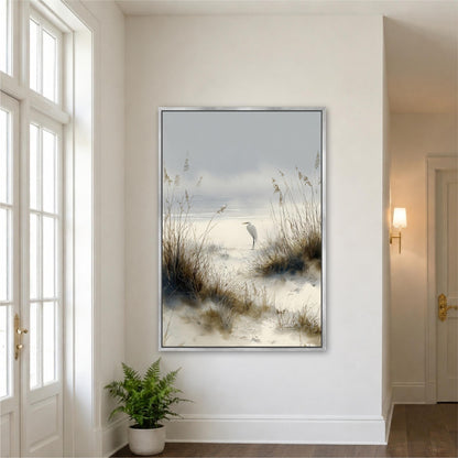 a large framed painting of a serene beach scene with a bird standing on the sand and tall grasses in the background.