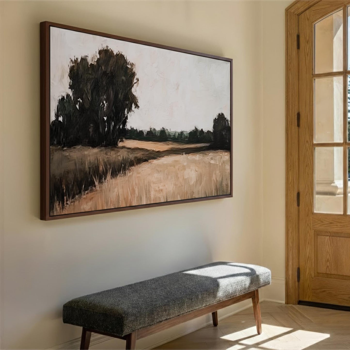 a large landscape painting hanging on a wall, with a wooden bench placed in front of it.