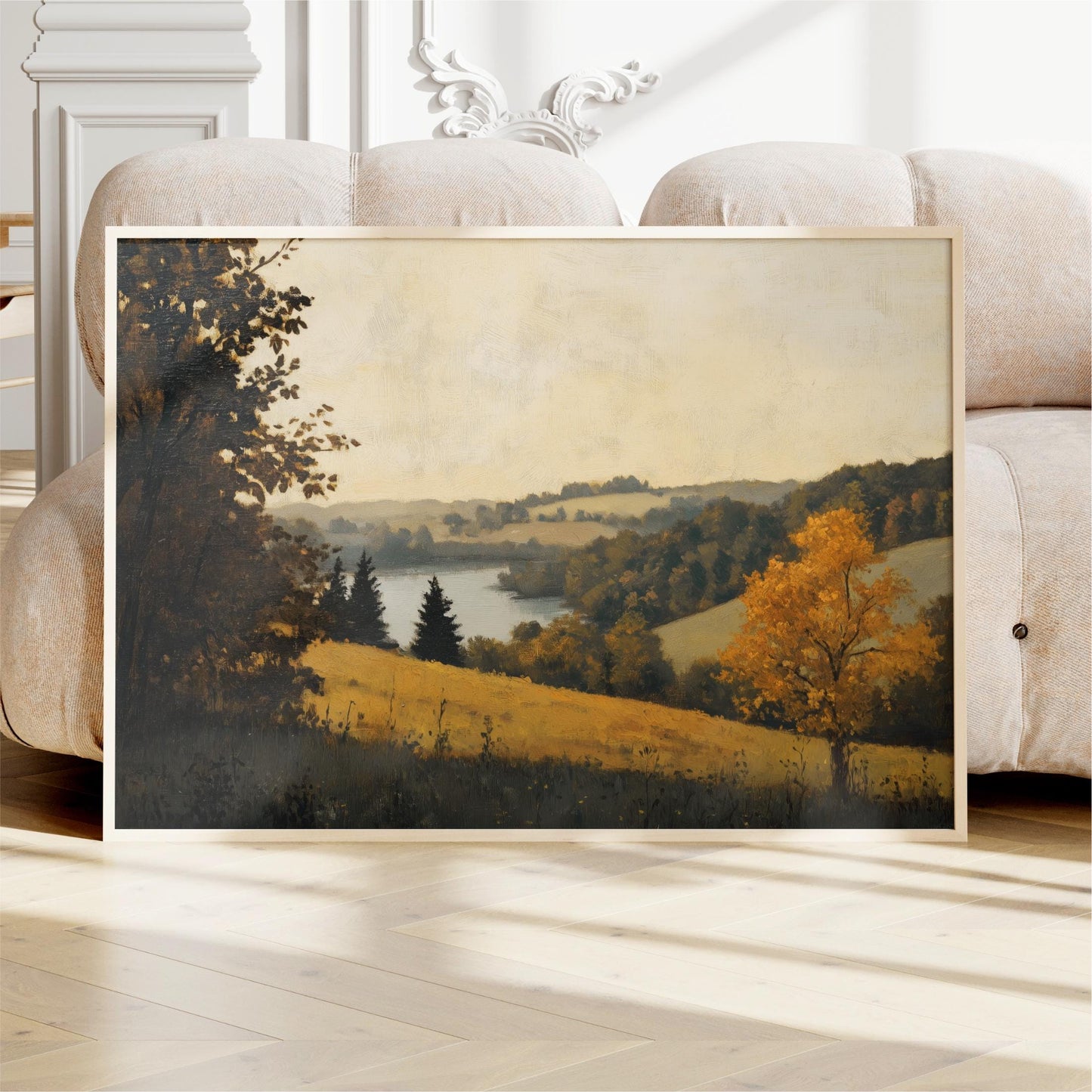 a framed landscape painting depicting a serene countryside scene with rolling hills, trees, and a body of water.